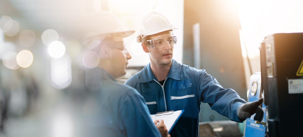 Dos maquinistas con cascos y gafas de protección manipulando una máquina