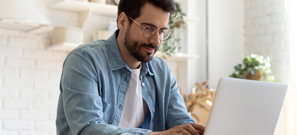 Happy man working on laptop with a background full of plants