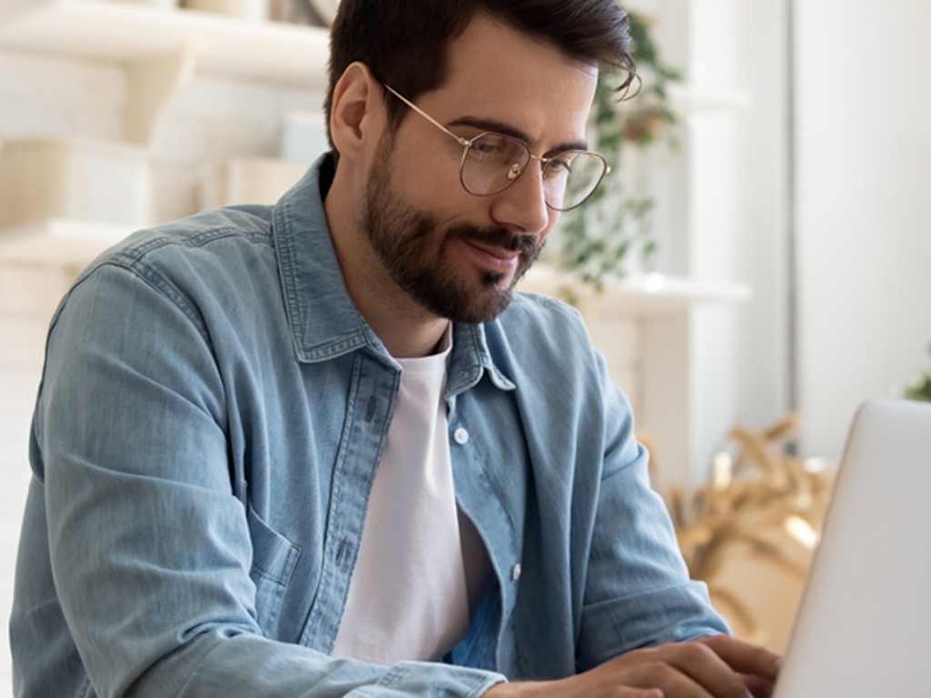 Happy man working on laptop with a background full of plants 