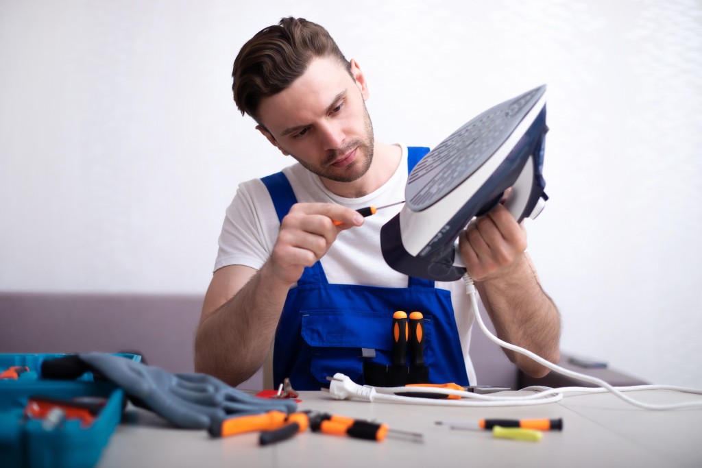 Technician using a screwdriver to repair an iron 