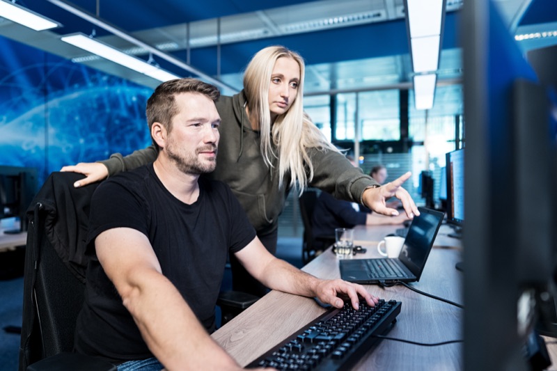 Two colleagues (man and woman) reviewing data on a computer screen in an office environment